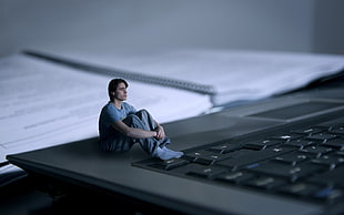 photo of man sit holding knee on laptop computer