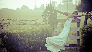 woman in white strapless wedding dress between bushes