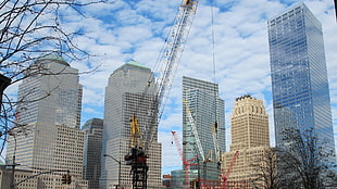 low angle photography of crane and high rise building under blue sky at daytime