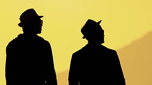 silhouette of two man with yellow background