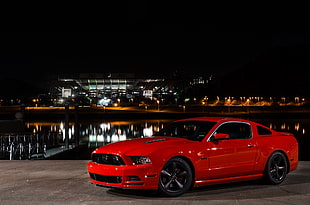 red Ford Mustang parked near bay during night time