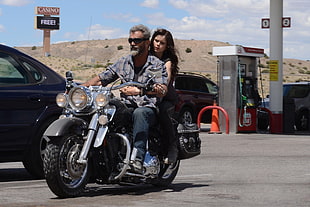man in gray button-up shirt riding black touring motorcycle with woman in gasoline station HD wallpaper