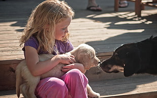 girl holds tan puppy