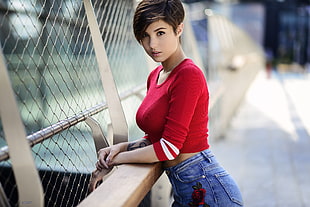short-haired woman in red long-sleeved crop top and blue jeans