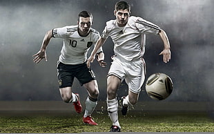 two soccer players chasing ball in field