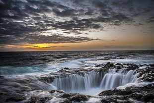photo of waterfalls in the middle of rocky ocean terrain HD wallpaper