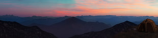 brown dome tent on top of mountain summit near mountains under white cloudy sky during sunset