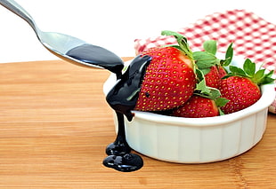 strawberries on white ceramic bowl topped with chocolate syrup