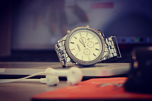 selective focus photo of round silver-colored chronograph watch with link band