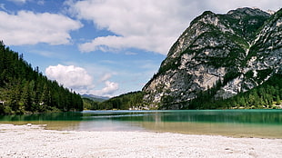 gray rock formation near body of water under blue and white sky