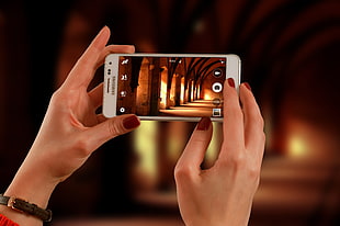 person taking photo of building interior using white Samsung Galaxy J2 HD wallpaper