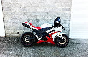 white, black and red Yamaha sports bike with full face helmet