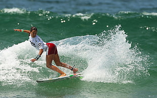 woman in white shirt with red shorts playing surfboard during daytime HD wallpaper