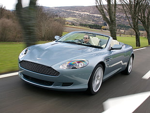 man riding gray Aston Martin convertible coupe on road during daytime