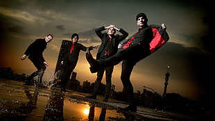 four men in black-and-red suit jackets and black pants