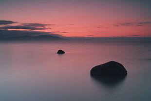 two rocks on calm body of water HD wallpaper