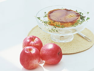 three ripe apples beside clear glass footed bowl