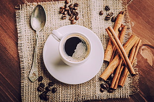 closeup photo of coffee in white mug beside spoon
