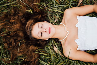 woman in strapless dress lying on ground with eyes closed during daytime