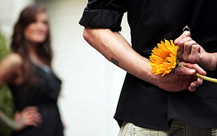 shallow focus photography of man holding flower and ring at his back