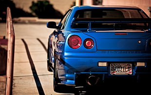 blue Nissan GT-R R34 Skyline coupe parked during daytime