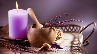 purple lighted pillar candle beside a brown mortar and pestle on the tray