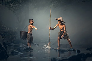 two boys catching fish on river