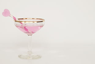 cocktail glass with pink liquid and white and pink stripe straw