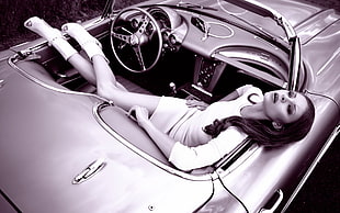 grayscale photography of woman laying on convertible coupe