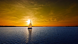sailing boat on body of water during sunset