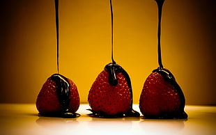 chocolate pouring on three strawberries