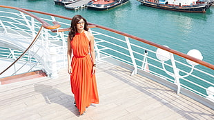 woman wearing orange sleeveless dress walking on ship deck during daytime
