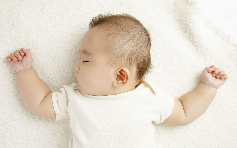 baby in white top lying on white surface HD wallpaper