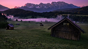 brown wooden shed near lake and glacier mountain during golden hour