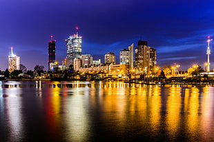 cityscape of lighted buildings near body of water, uno city, vienna HD wallpaper