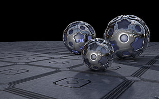 three round grey metal balls near grey surface