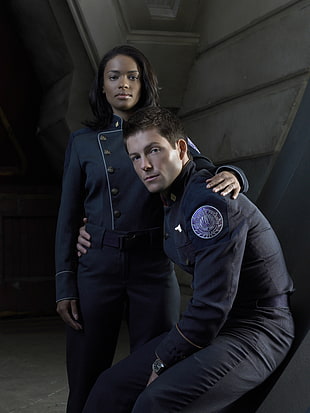 man wearing black jacket sitting beside standing woman wearing black button-up jacket