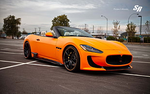orange Tesla convertible coupe on gray parking lot HD wallpaper