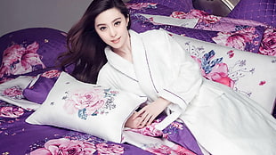 woman wearing white bathrobe lying on purple and pink floral comforter