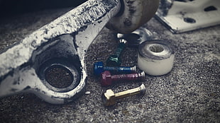 four gray metal bolts, skateboard, screws 