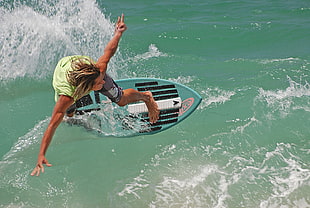 man wearing green tank top surfing during daytime