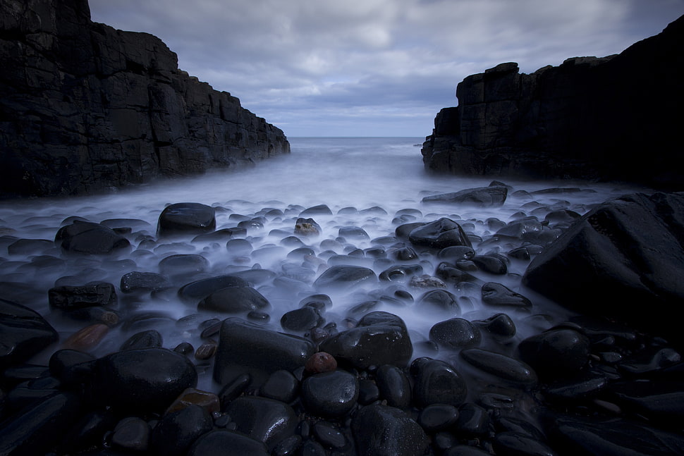 black rocks one sea shore under white clouds HD wallpaper