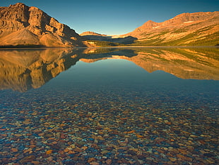 body of water near brown mountain