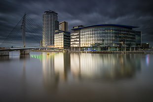 gray and white glass wall building near body of water and bridge, salford quays