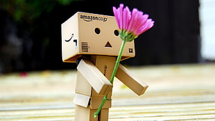 Box character holding pink flower shallow focus photography