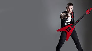 man carrying red flying electric guitar
