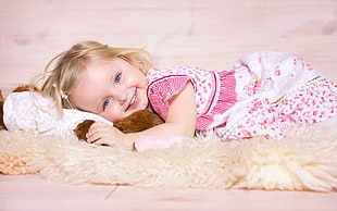 girl wearing white and pink dress laying on a white fur textile