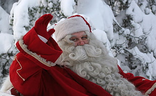 panoramic photo of Santa Claus mascot waving in front of snow covered tree
