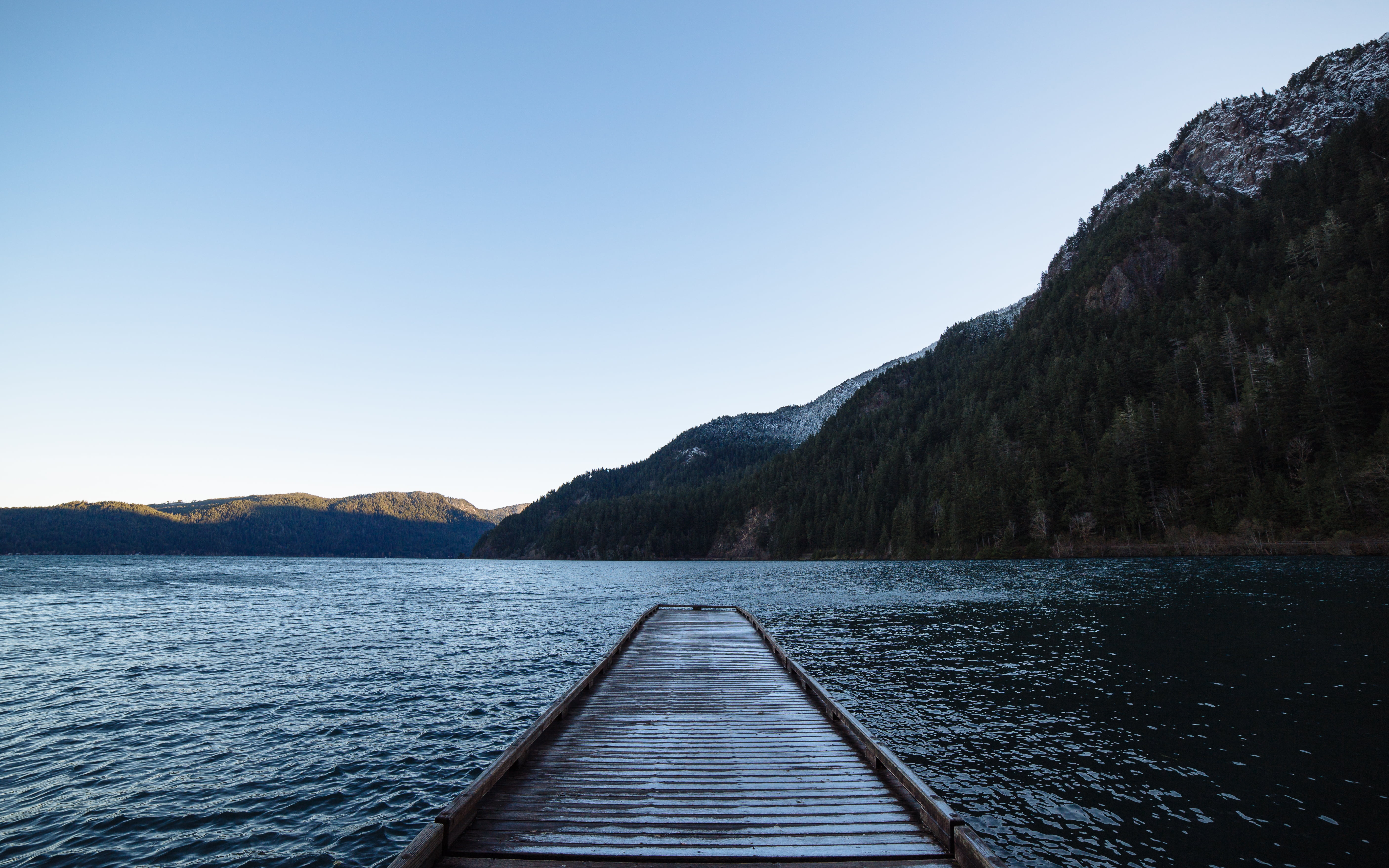 gray wooden dock in front of body of water and mountain