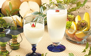 two clear glasses with white liquor on brown surface